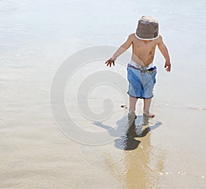 Boy (3-4) playing on beach back view