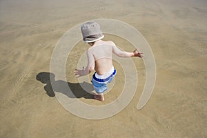 Boy (3-4) playing on beach back view