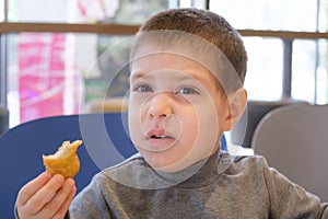 A boy of 4 years old eats nuggets with sauce in a fast food cafe.