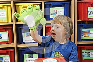 Boy (5-6) with Down syndrome playing with finger puppets in kindergarten