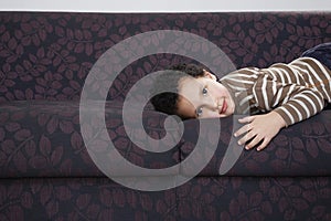 Boy (5-6) lying on sofa portrait