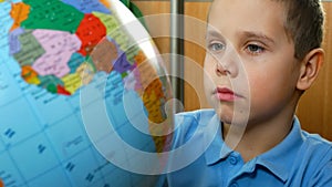 A boy of 6-7 years old examines a globe. Teaching children at school. Children and Geography.