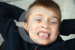 A boy of 6-7 years old shows the first teeth that grow after the loss of milk teeth