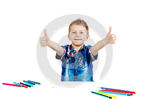 A boy of 6 years in a blue shirt shows a thumbs up on a white background isolate. The concept is all ok