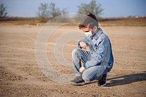 A boy of 8-9 years old in a protective mask and jeans clothes outdoors