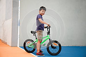 A boy, 8 years old, with a bike standing outdoors in a park