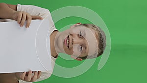 Boy of 9 years holds a sheet of paper. Green screen.Closeup