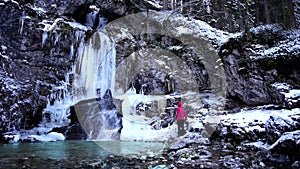 Boy admires the stalactites on the Valesinella waterfall in winter