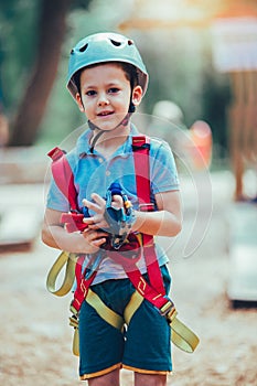 Boy in adventure activity park with helmet and safety equipment