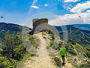 A boy against the background of the Gunib fortress. A protective wall. Russia, Dagestan. June 2021