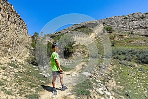 A boy against the background of the Gunib fortress. A protective wall. Russia, Dagestan. June 2021