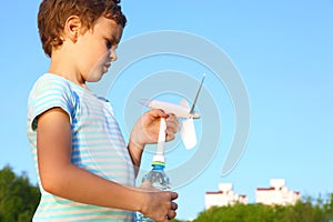 Boy against sky plays with wind-driven generator