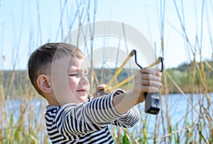 Boy Aiming Sling Shot Outdoors by Lake