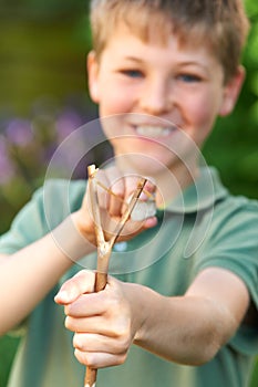Boy Aiming Slingshot In Garden