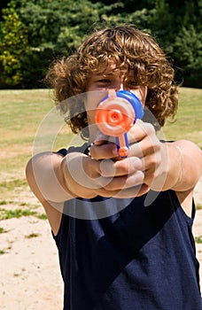 Boy aiming water gun at you