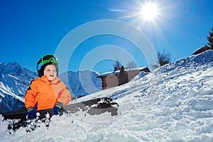 Boy on alpine ski track sit wear helmet ang mask over mountain