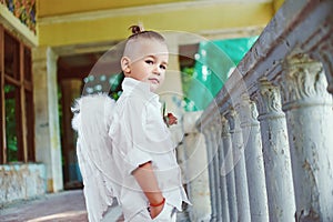 Boy with angel wings on old city background