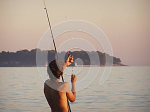 Boy angling at sunset