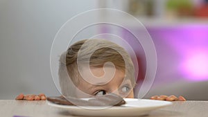 Boy appearing from under table and stealing piece of chocolate bar, sweet-tooth