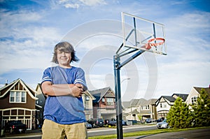 Boy with arms crossed with basketball net smiling