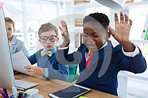 Boy as business executive laughing while looking at digital tablet