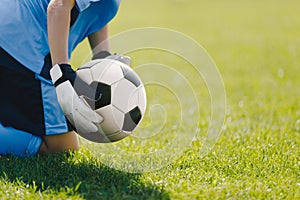 Boy as a football goalie holding the ball in their hands ready to start a game. Football goalkeepers play a football match