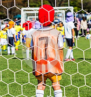 A boy as a goalie or goalkeeper waiting during a children soccer game.