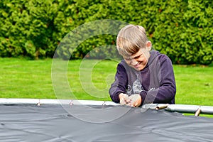 The boy assembles a new trampoline and tensions the springs