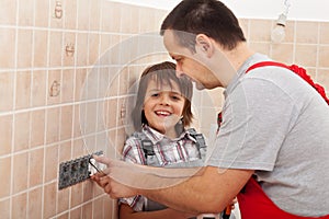 Boy assisting his father installing electical outlets