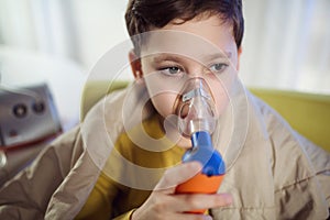 Boy with asthma problems making inhalation with mask on her face