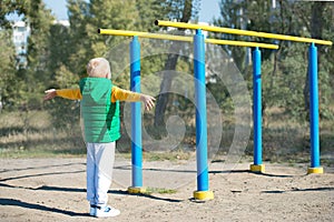 Boy athlete doing pull ups.Active lifestyle. The child performs exercises on uneven bars on the street.