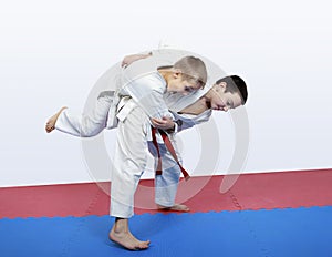 Boy athlete with a red sash makes hip throw