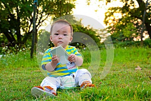 Boy/baby playing mobile phones on the lawn (Asia China)