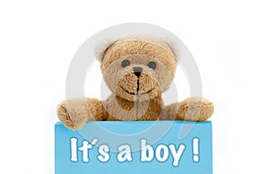 Boy baby shower ItÂ´s a boy message written on blue card with brown teddy bear holding with the two hands the note with the