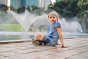 Boy on background of Fountain on the lake in the evening, near by Twin Towers with city on background. Kuala Lumpur