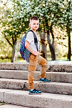 A boy with a backpack behind his back goes to school