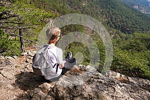 Boy with backpack enjoys beautiful view from mountain