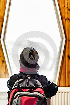 Boy with backpack looking out the window