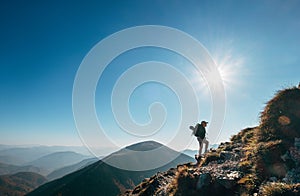 Boy backpacker traveler walk up on mountain top in contrast sun