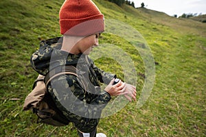 Boy with bacpack looking at his smart watches while hiking photo