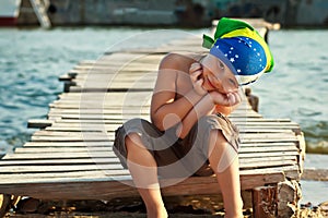 Boy in bandana sitting on wooden bridge in sand sunny summer day