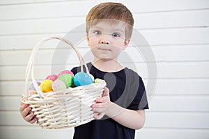 Boy with a basket with Easter eggs on a background of a white wall