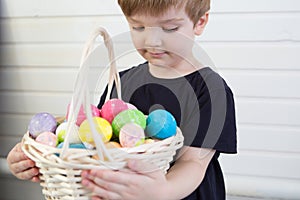 Boy with a basket with Easter eggs on a background of a white wall