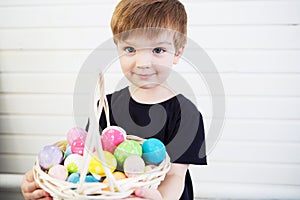 Boy with a basket with Easter eggs on a background of a white wall