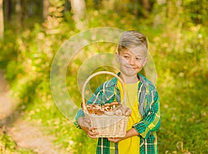 Boy with basket of mushrooms in autumn forest