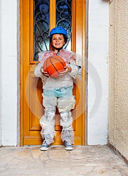 Boy with basketball ball near door in bubble wrap
