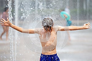 A boy bathes in a fountain in the heat and cools off on a warm day