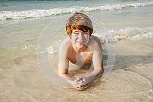 Boy in bathingsuit is lying at the beach