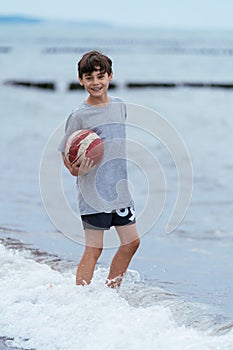 Boy on the beach with ball. Family vacation by the sea. Active lifestyle