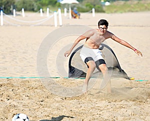Boy during beach football match on hot sand in summer